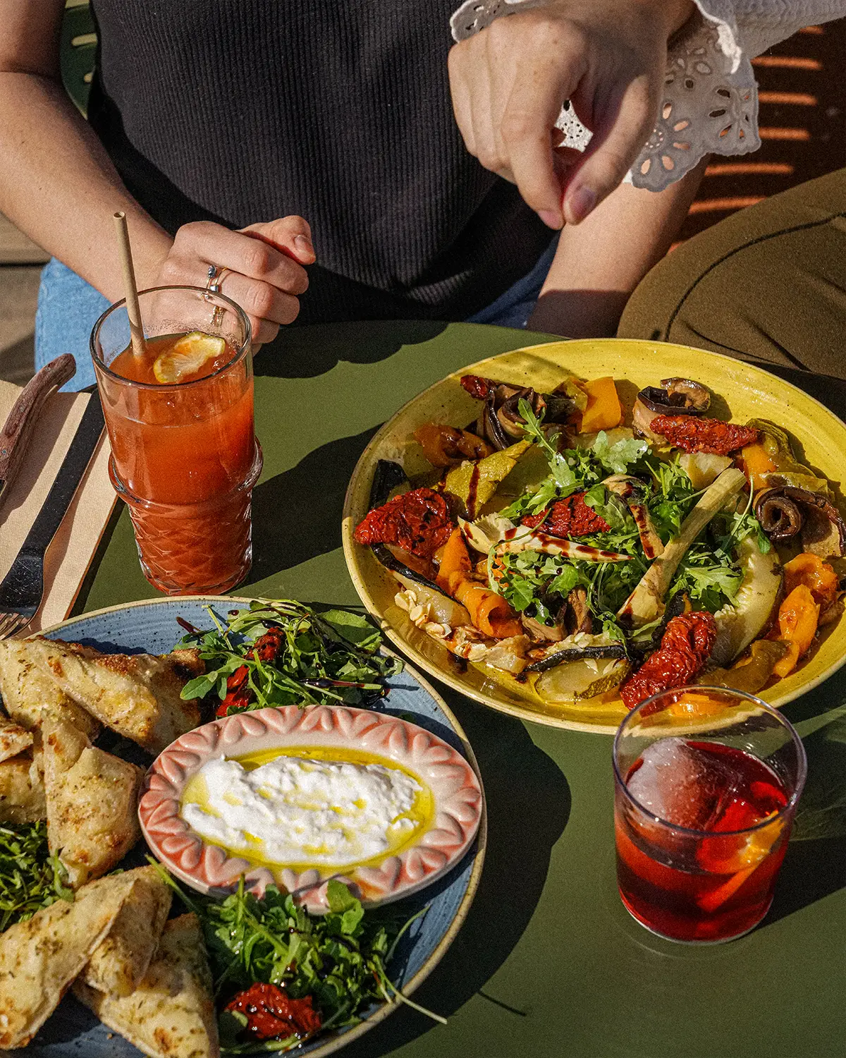 Antipasti en terrasse : légumes grillés, roquette, burrata et pain à pizza, avec un cocktail