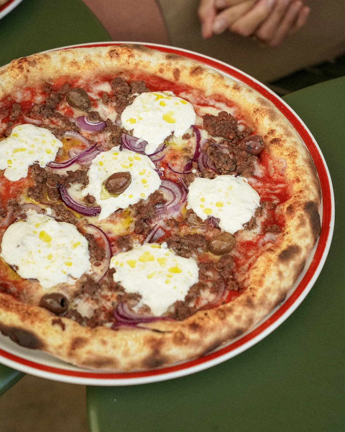 Pizza à la viande hachée, oignons rouges, olives et burrata, filet d'huile d'olive